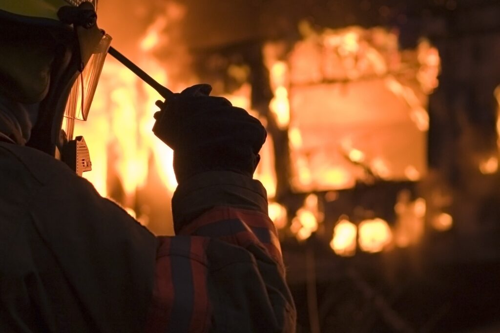 Firefighter using a radio in front of a burning building